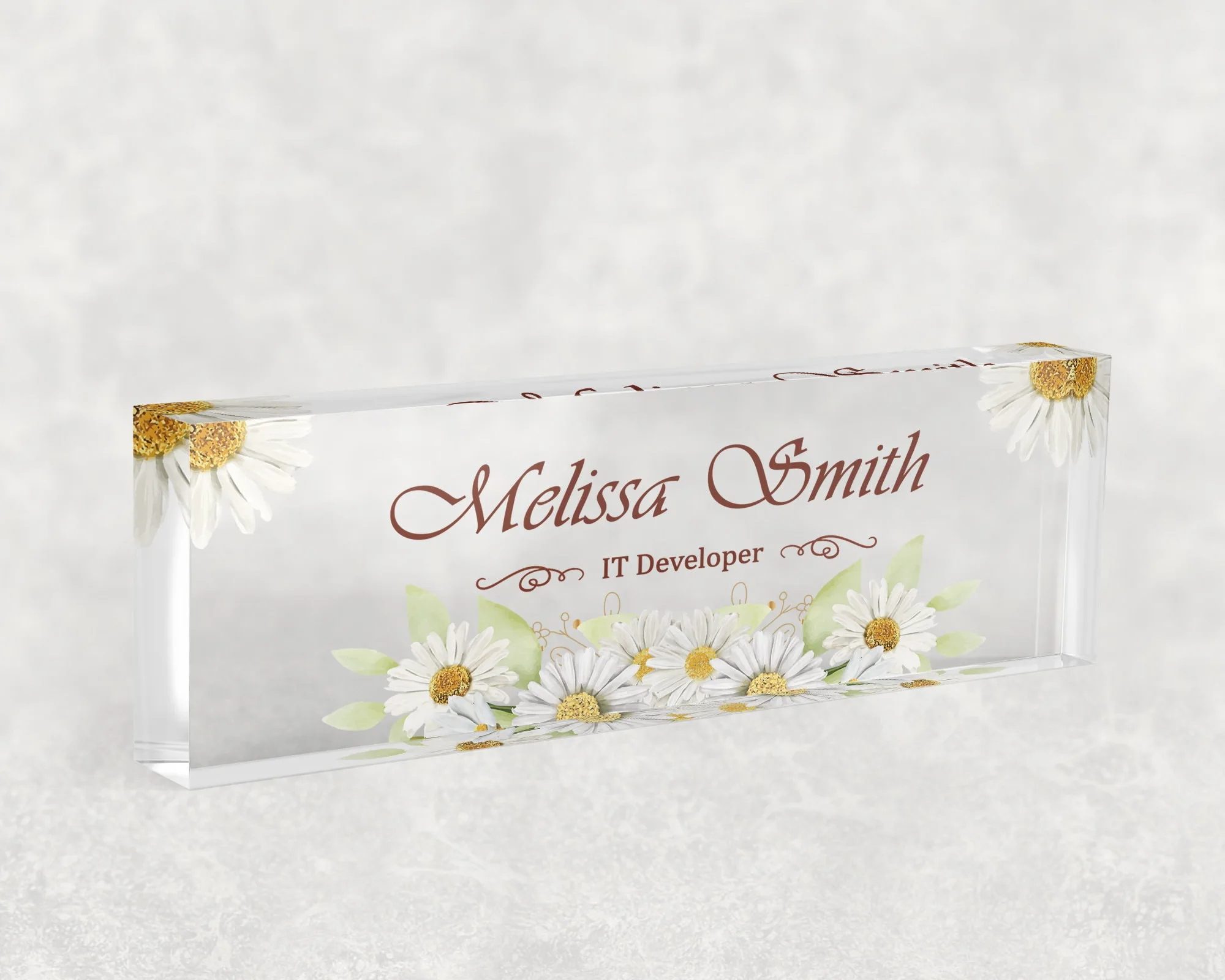 Studio view of a clear acrylic desk name plate with a white daisy design