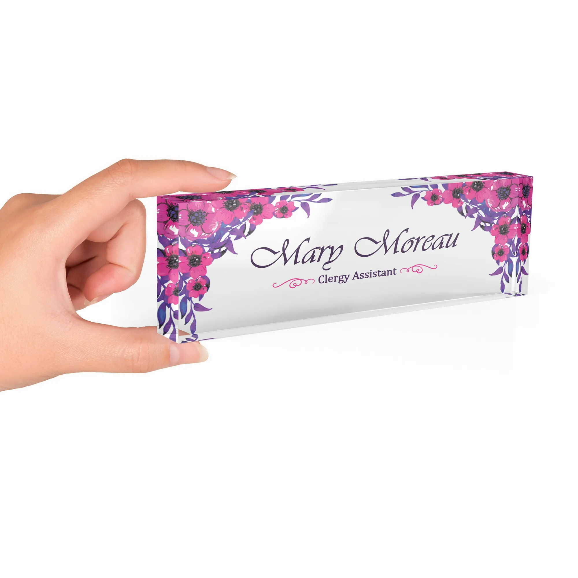 Hand holding a clear acrylic desk name plate with a fuchsia and violet floral design