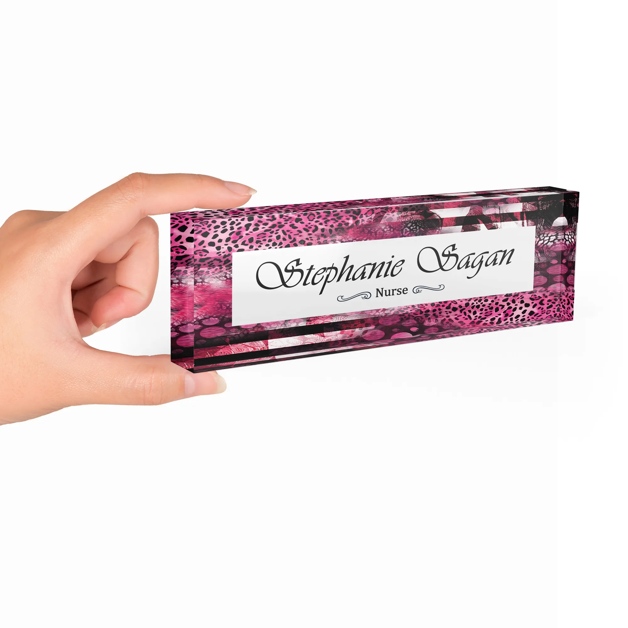 Hand holding a clear acrylic desk name plate with a fuchsia leopard design