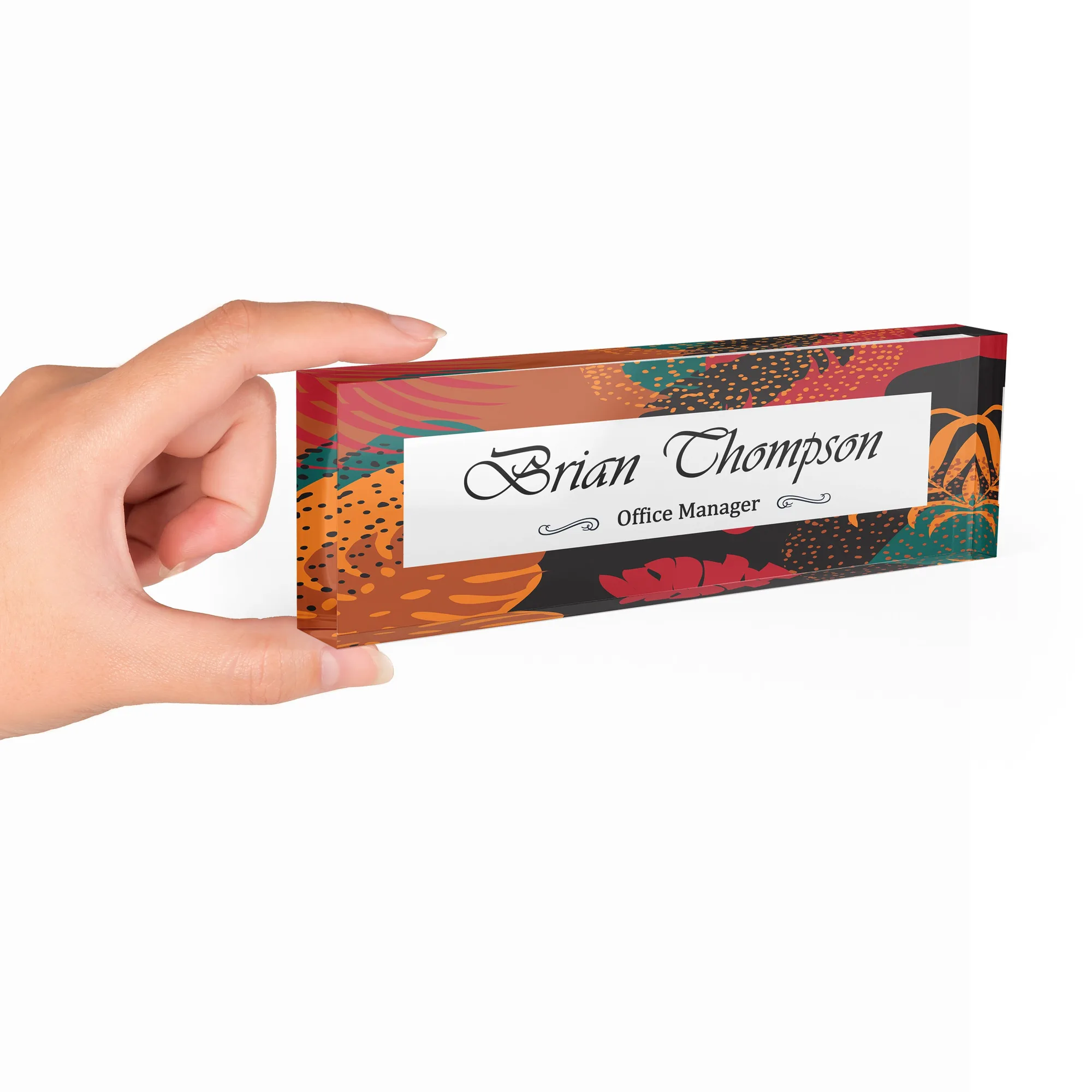 Hand holding a clear acrylic desk name plate with a dark botanical design