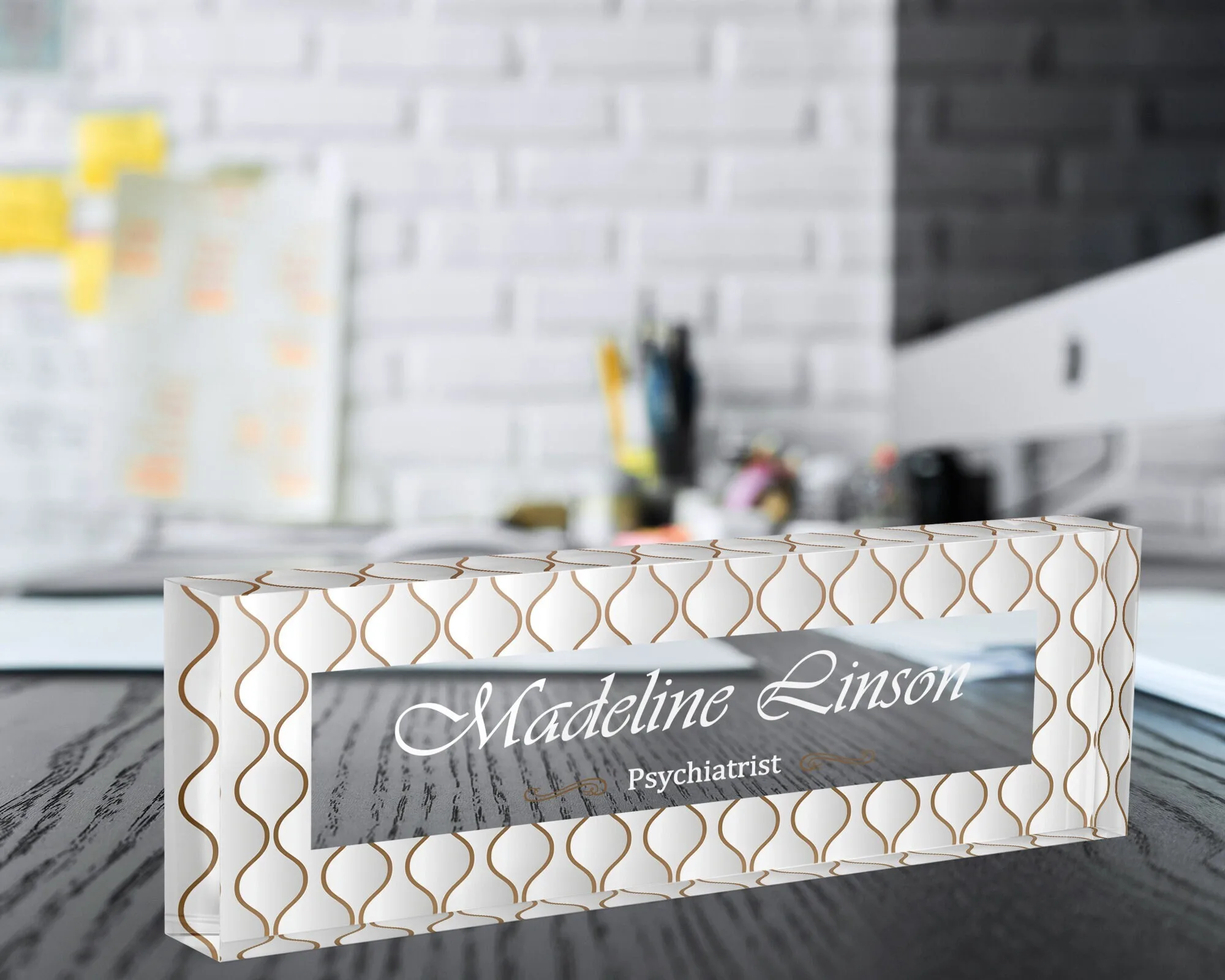 Personalized acrylic name plate with a gold scallop design on a dark wooden office desk