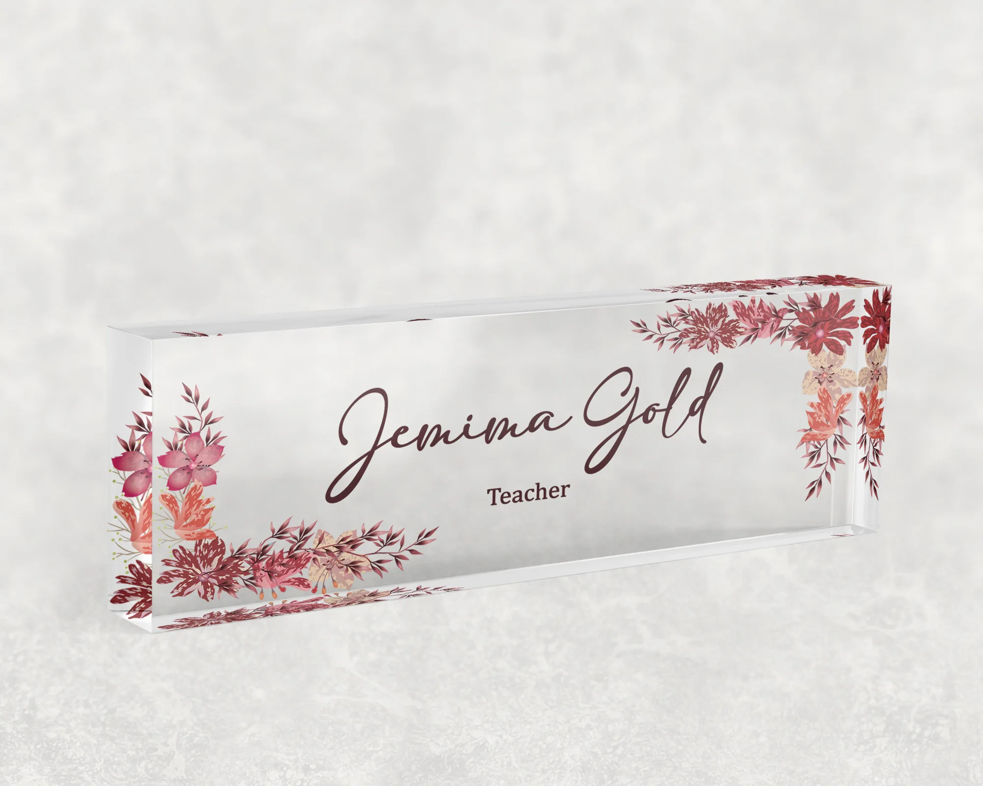 Studio view of a clear acrylic desk name plate with a coral autumn leaf design