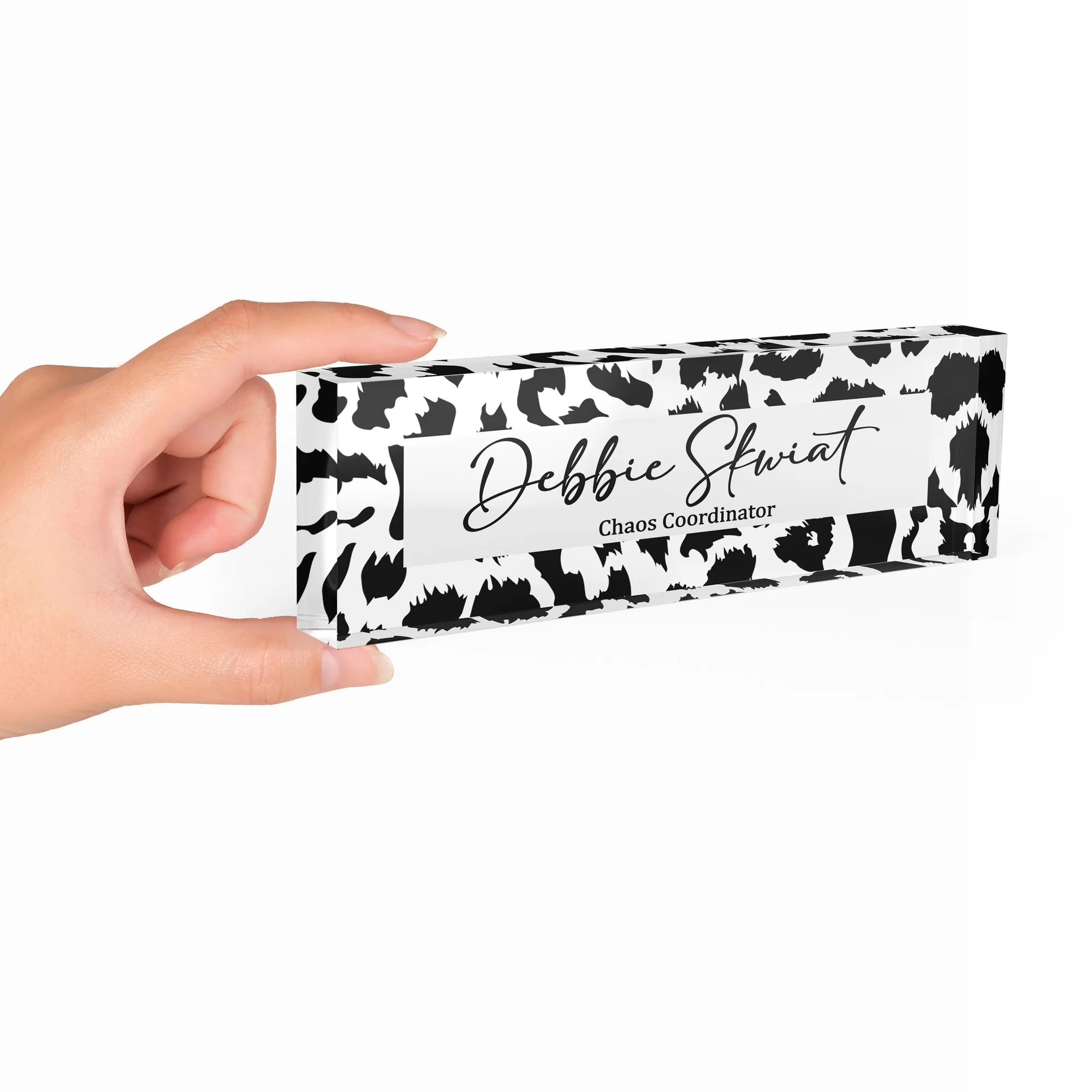 Hand holding a clear acrylic desk name plate with a black and white animal print design