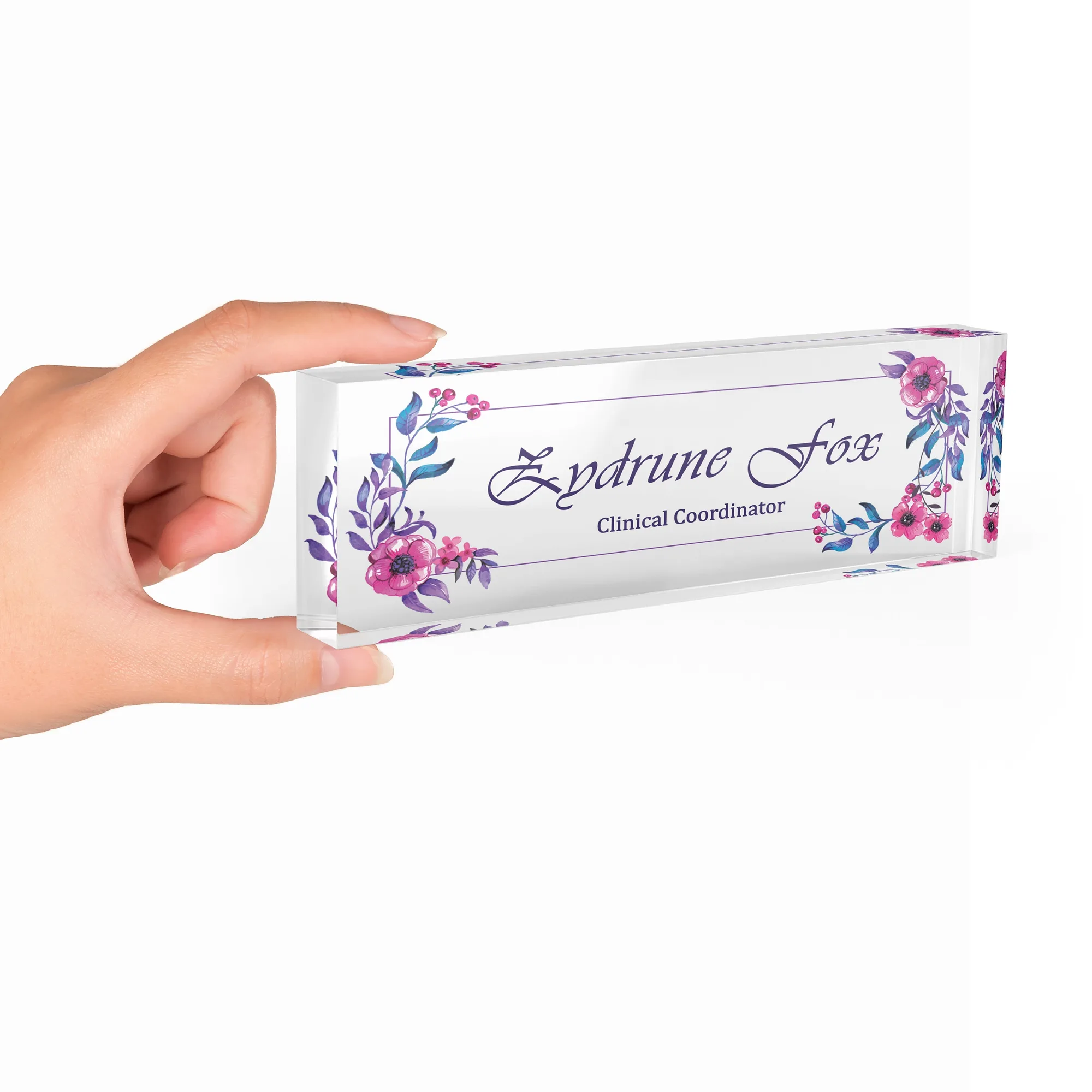 Hand holding a clear acrylic desk name plate with a pink and violet floral design