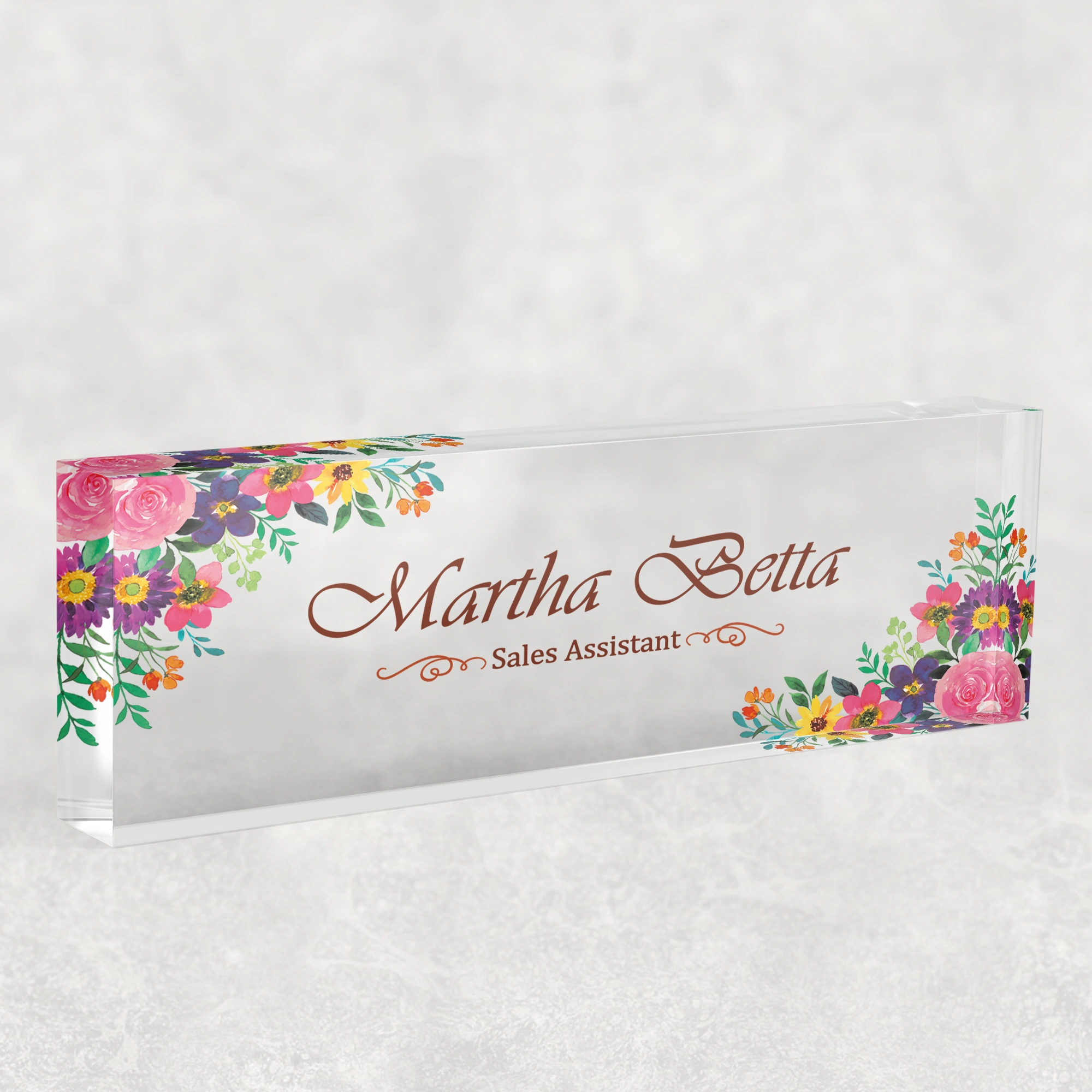 Studio view of a clear acrylic desk name plate with a folk floral design