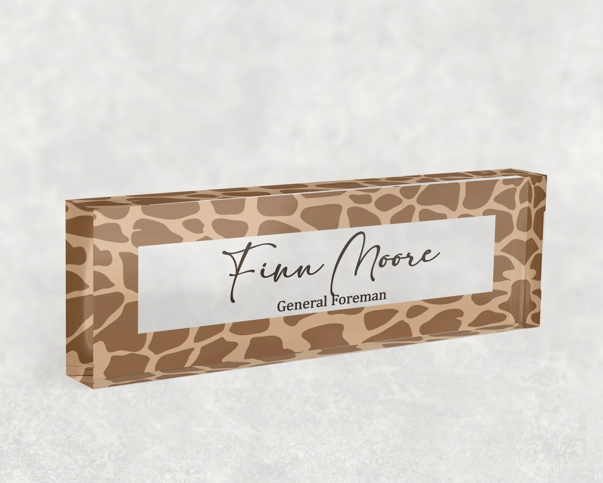Studio view of a clear acrylic desk name plate with a tan giraffe print design
