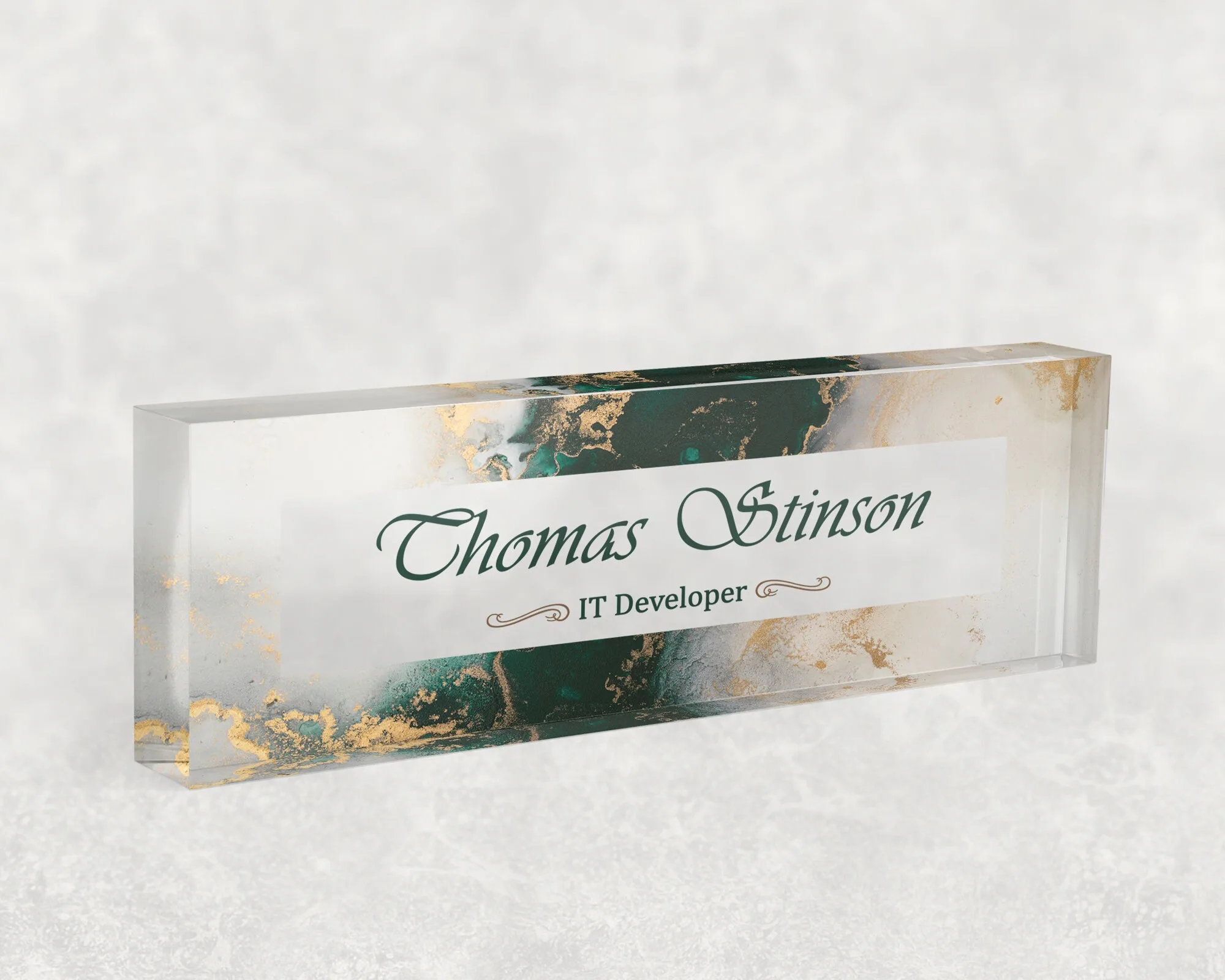 Studio view of a clear acrylic desk name plate with an emerald marble and gold design
