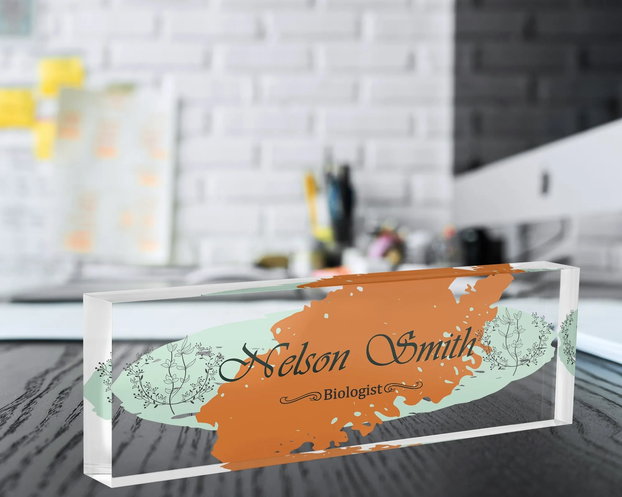 Personalized acrylic name plate with a terracotta brush stroke design on a dark wooden office desk