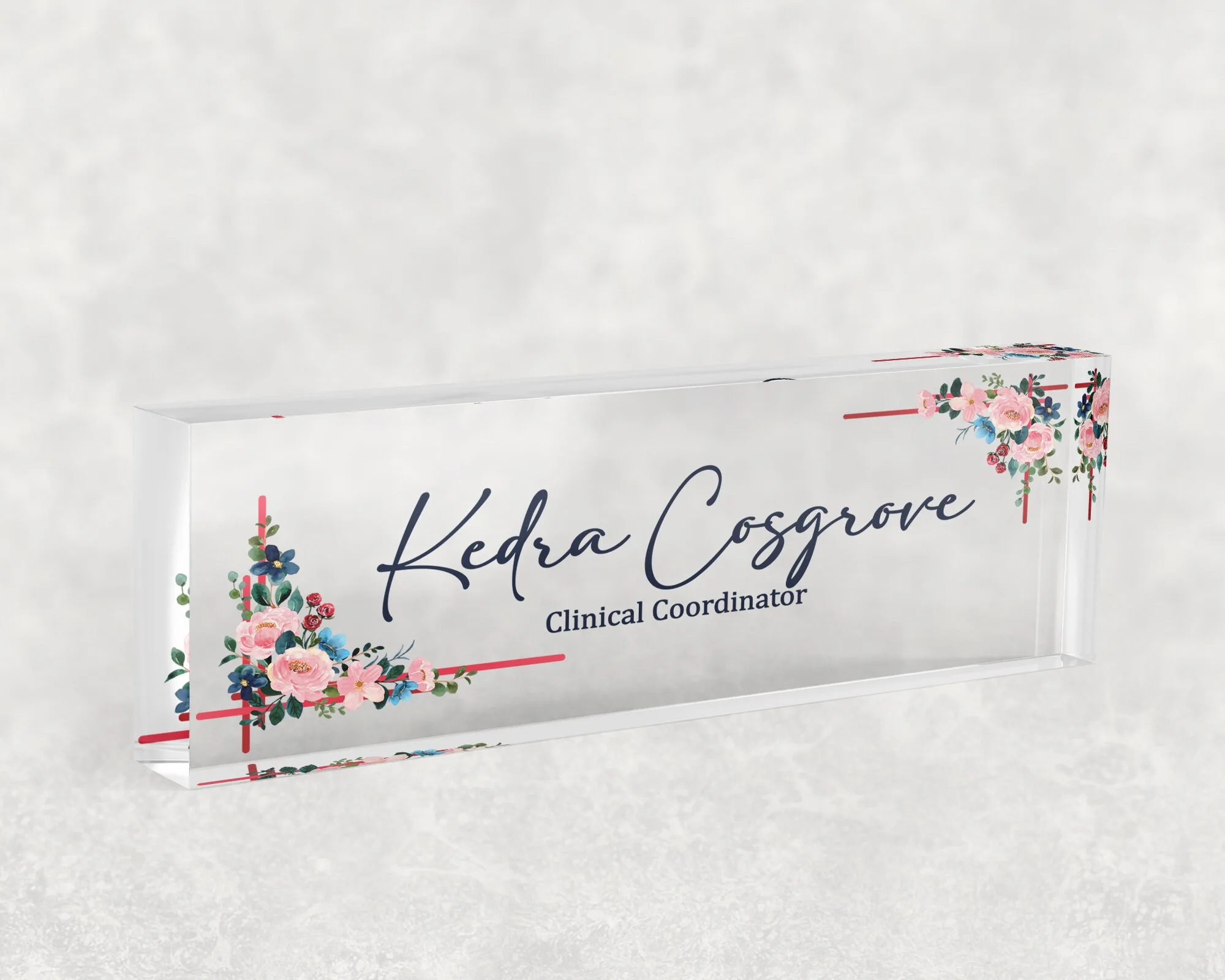 Studio view of a clear acrylic desk name plate with a pink and blue bouquet design