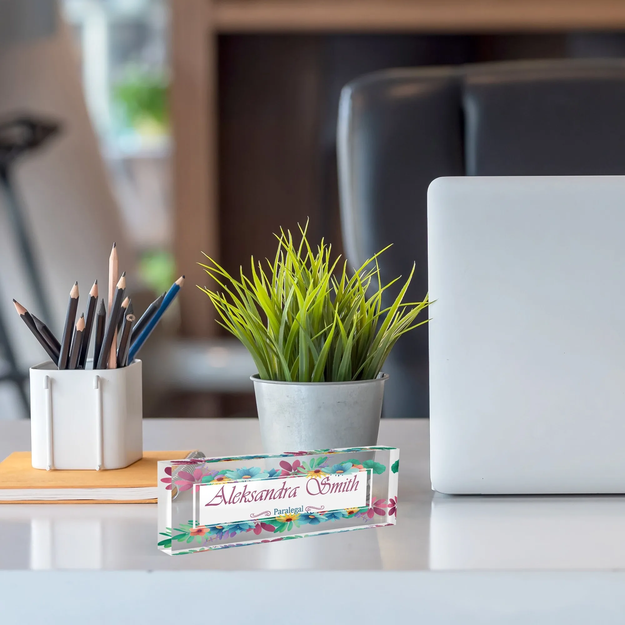 Personalized name plate with a watercolour bouquet design beside a pencil cup and a small plant on a home office desk