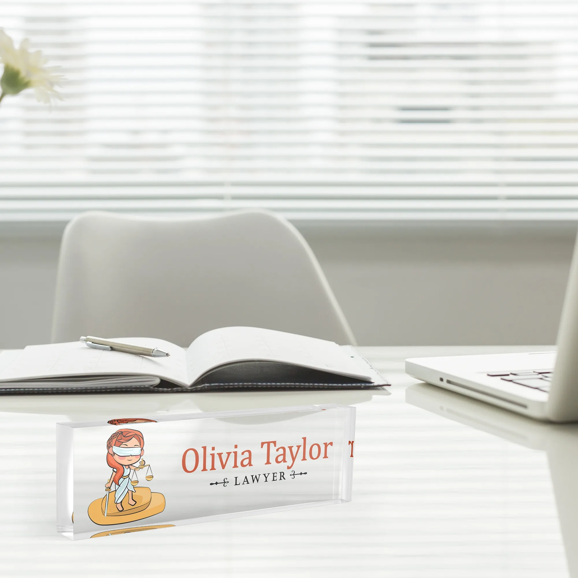 Acrylic desk name plate with an illustrated lawyer design beside an open notebook and a laptop