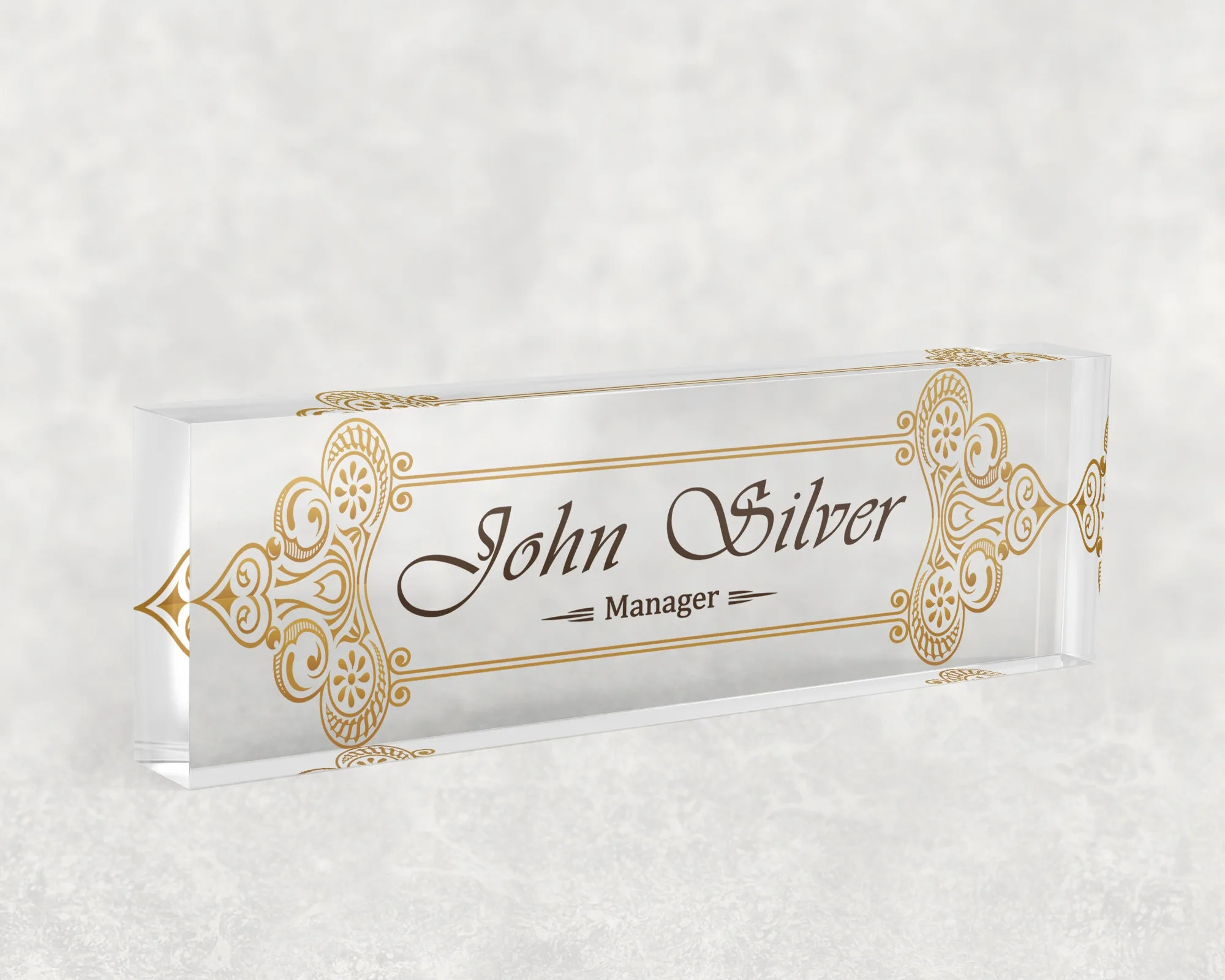 Studio view of a clear acrylic desk name plate with an ornate gold scroll design
