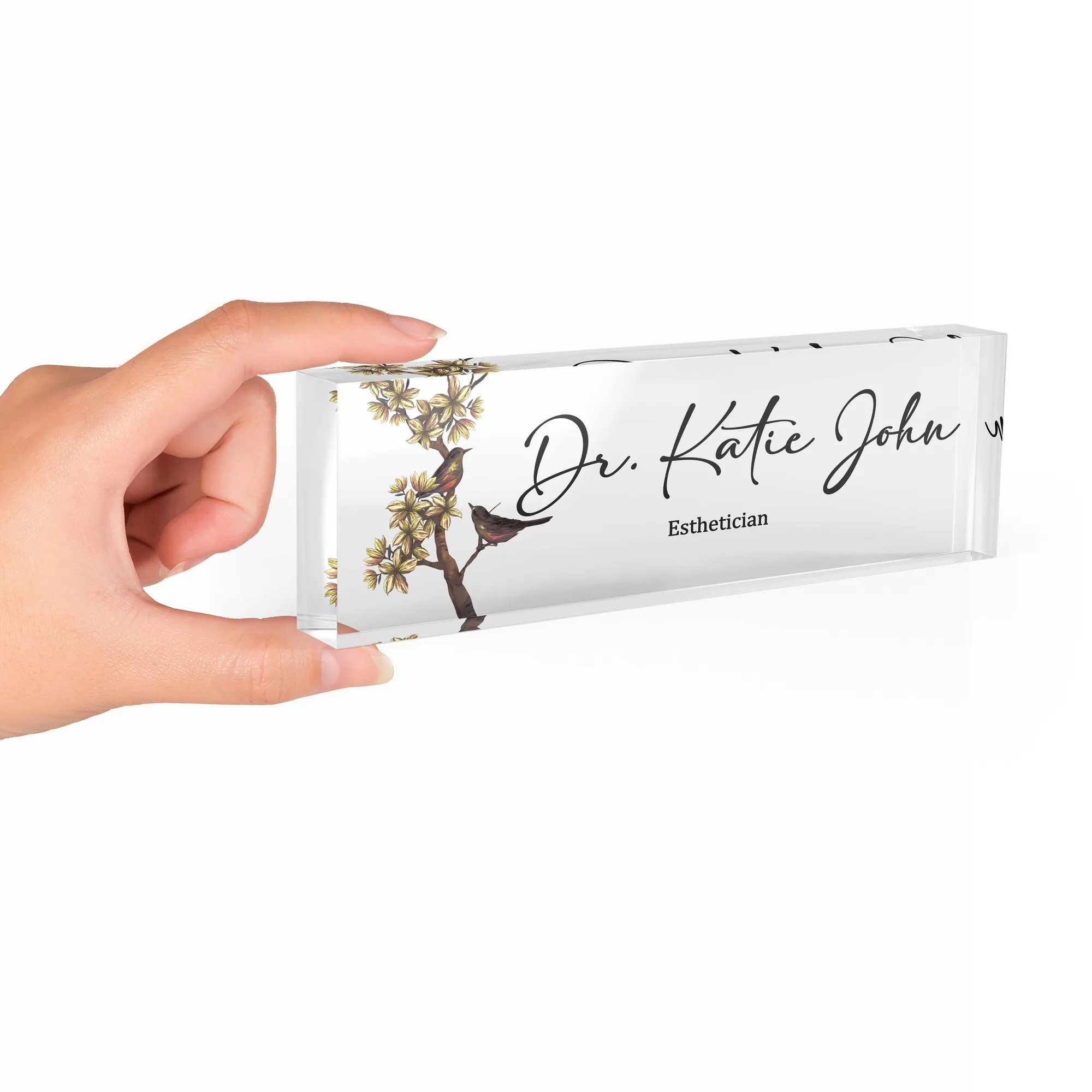 Hand holding a clear acrylic desk name plate with a bird and blossom branch design
