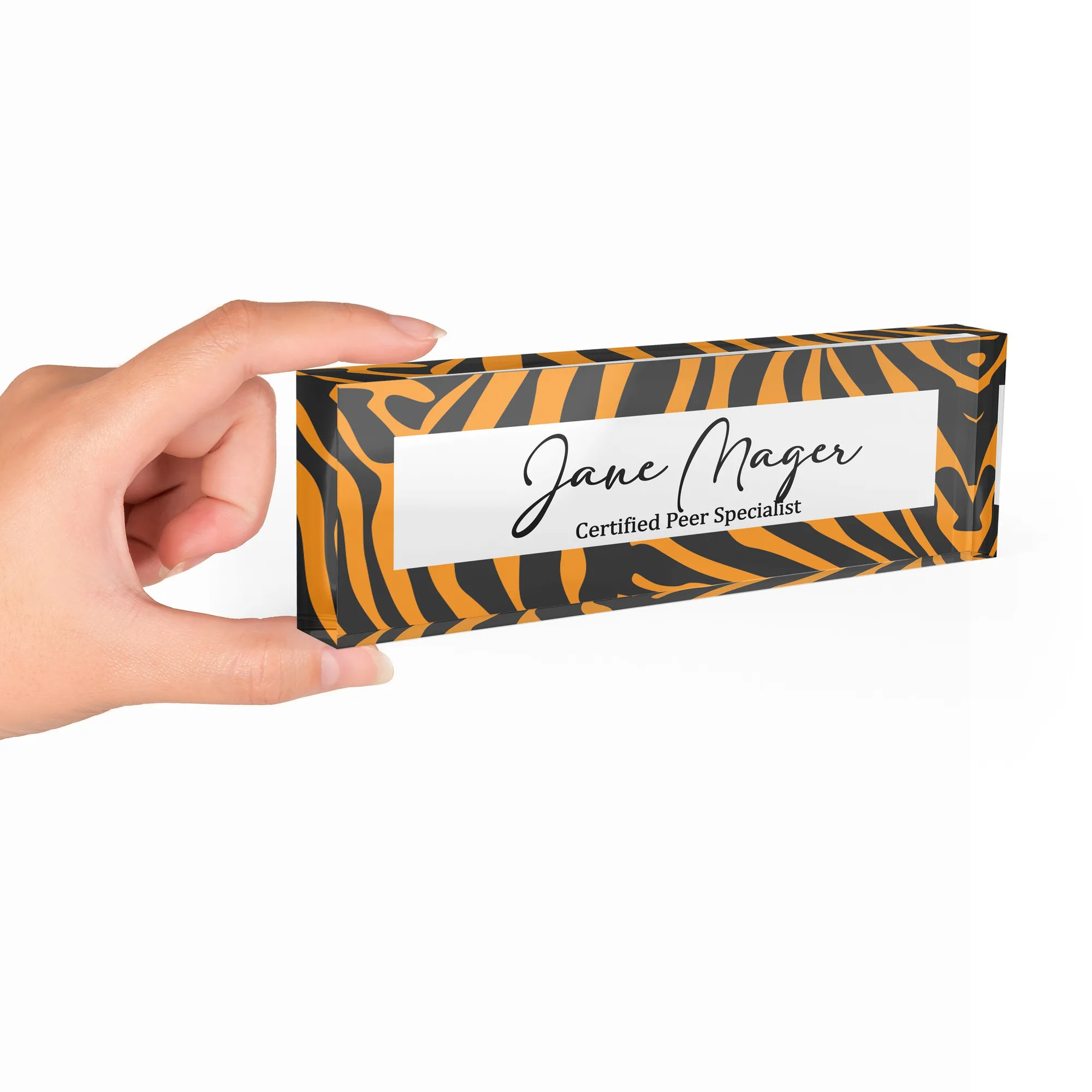Hand holding a clear acrylic desk name plate with an amber tiger stripe design