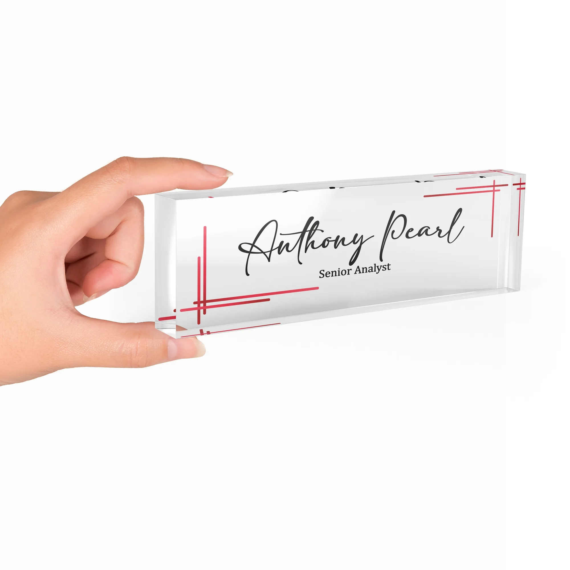Hand holding a clear acrylic desk name plate with a minimal red line design