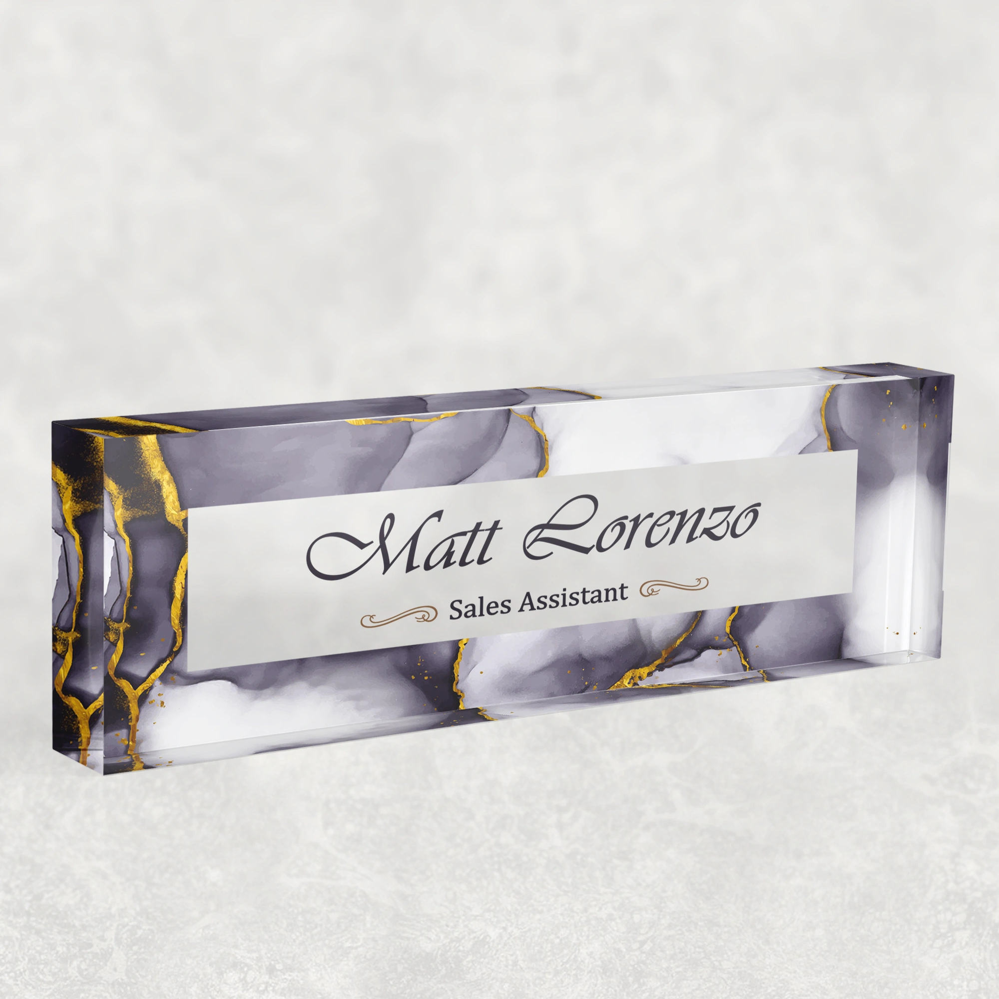 Studio view of a clear acrylic desk name plate with a grey marble and gold design
