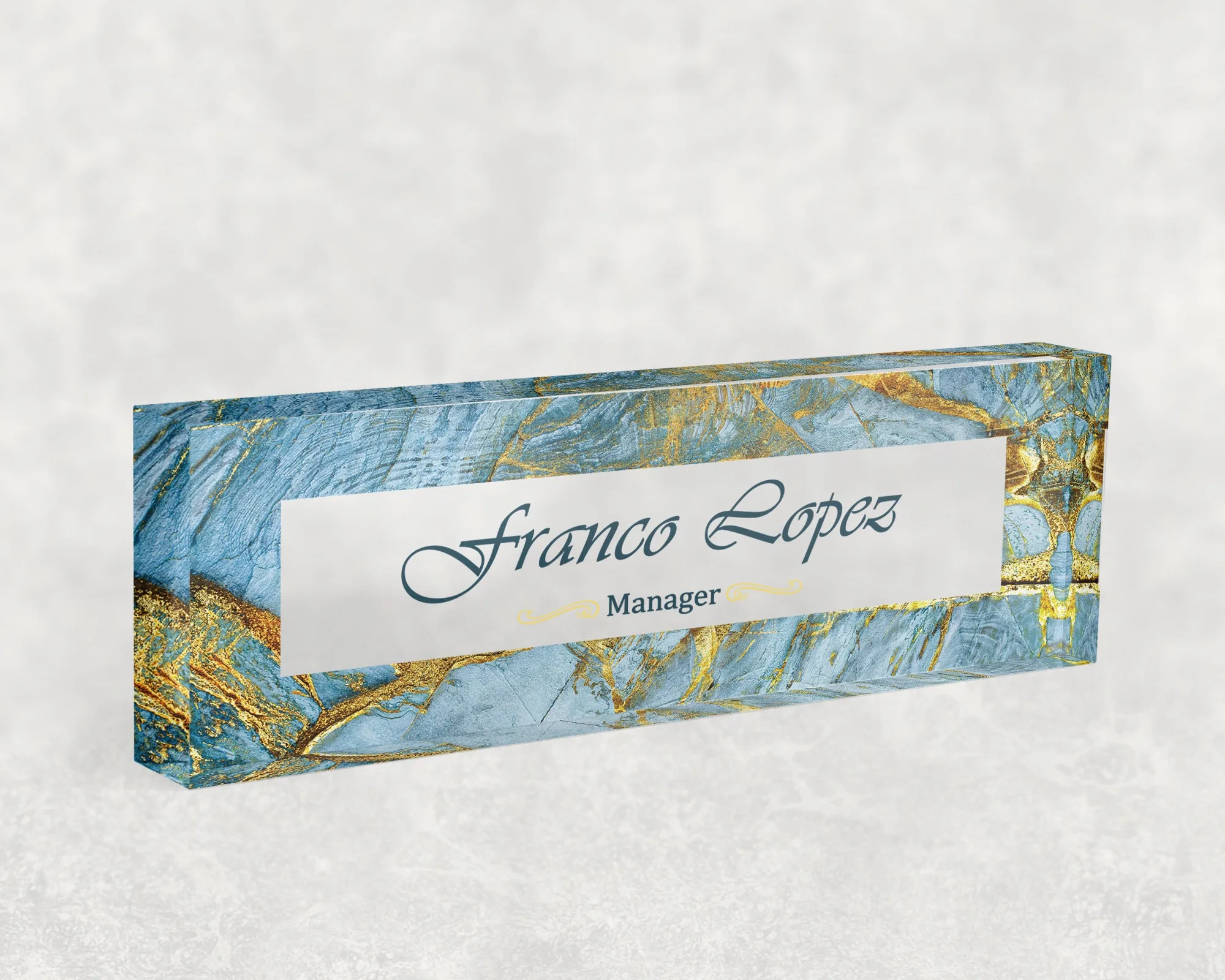 Studio view of a clear acrylic desk name plate with a blue agate and gold design