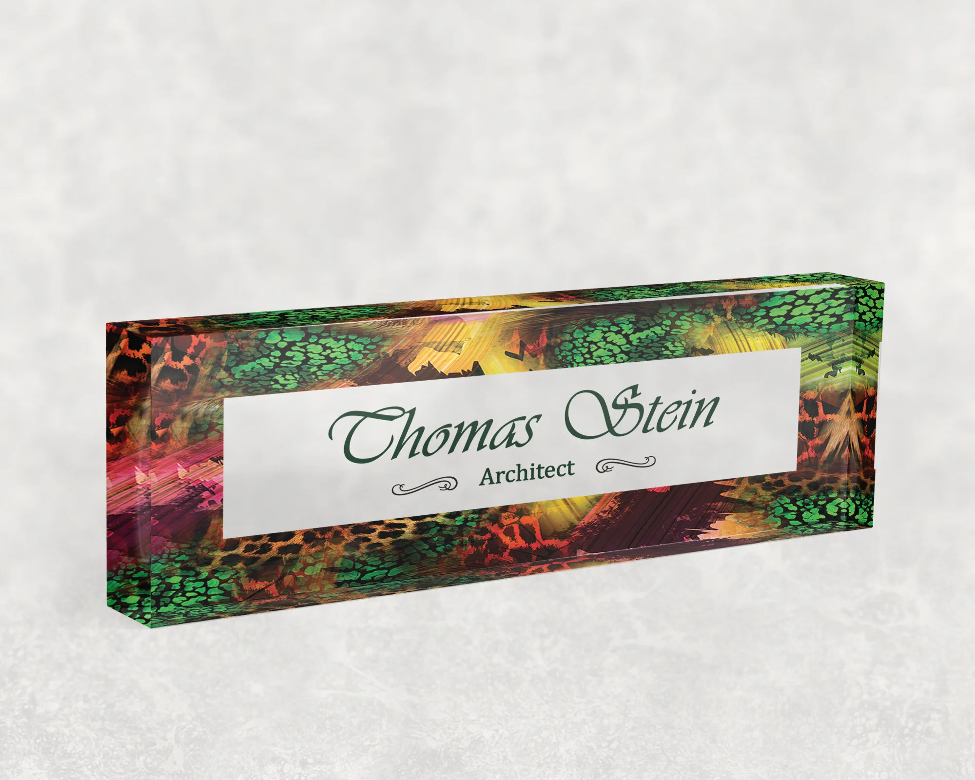 Studio view of a clear acrylic desk name plate with an emerald and gold leopard design