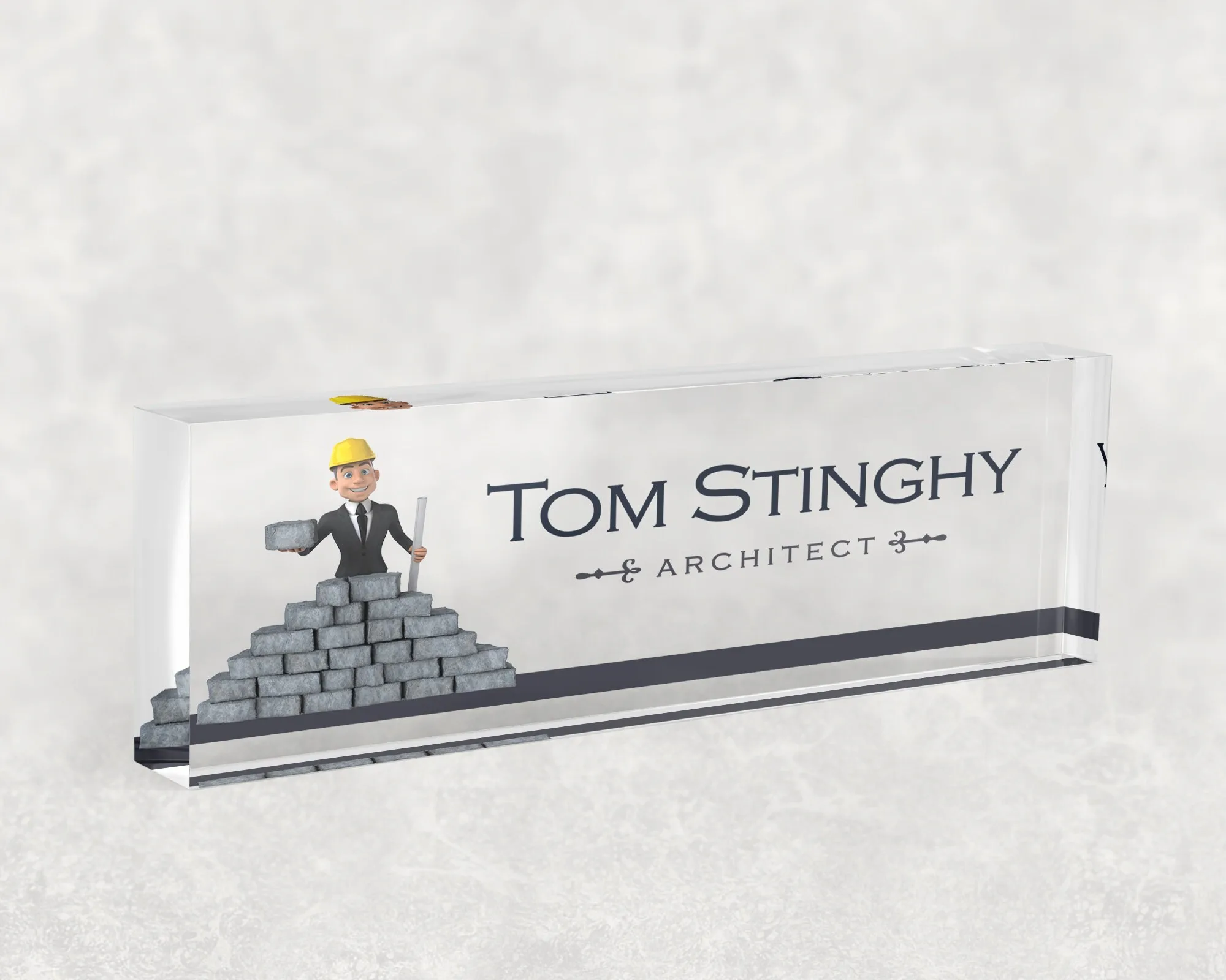 Studio view of a clear acrylic desk name plate with a comic architect design