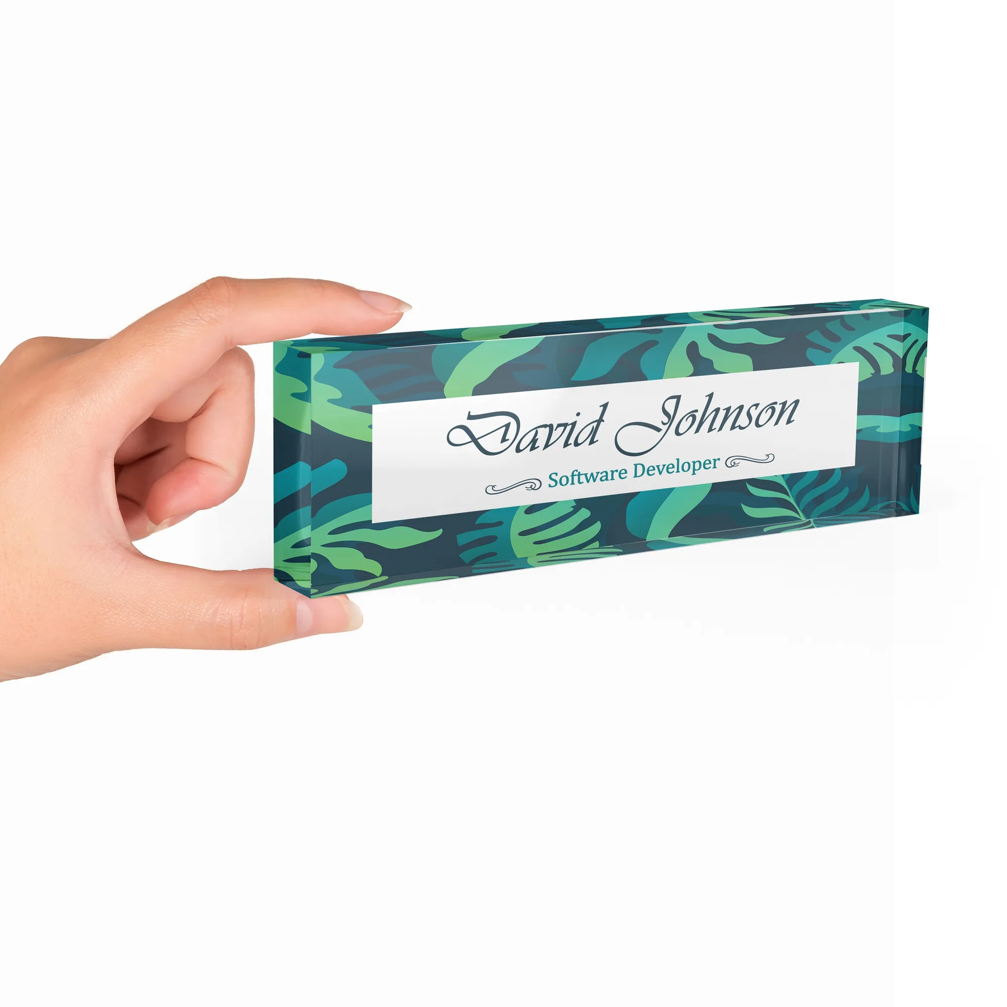 Hand holding a clear acrylic desk name plate with a jungle green leaf design