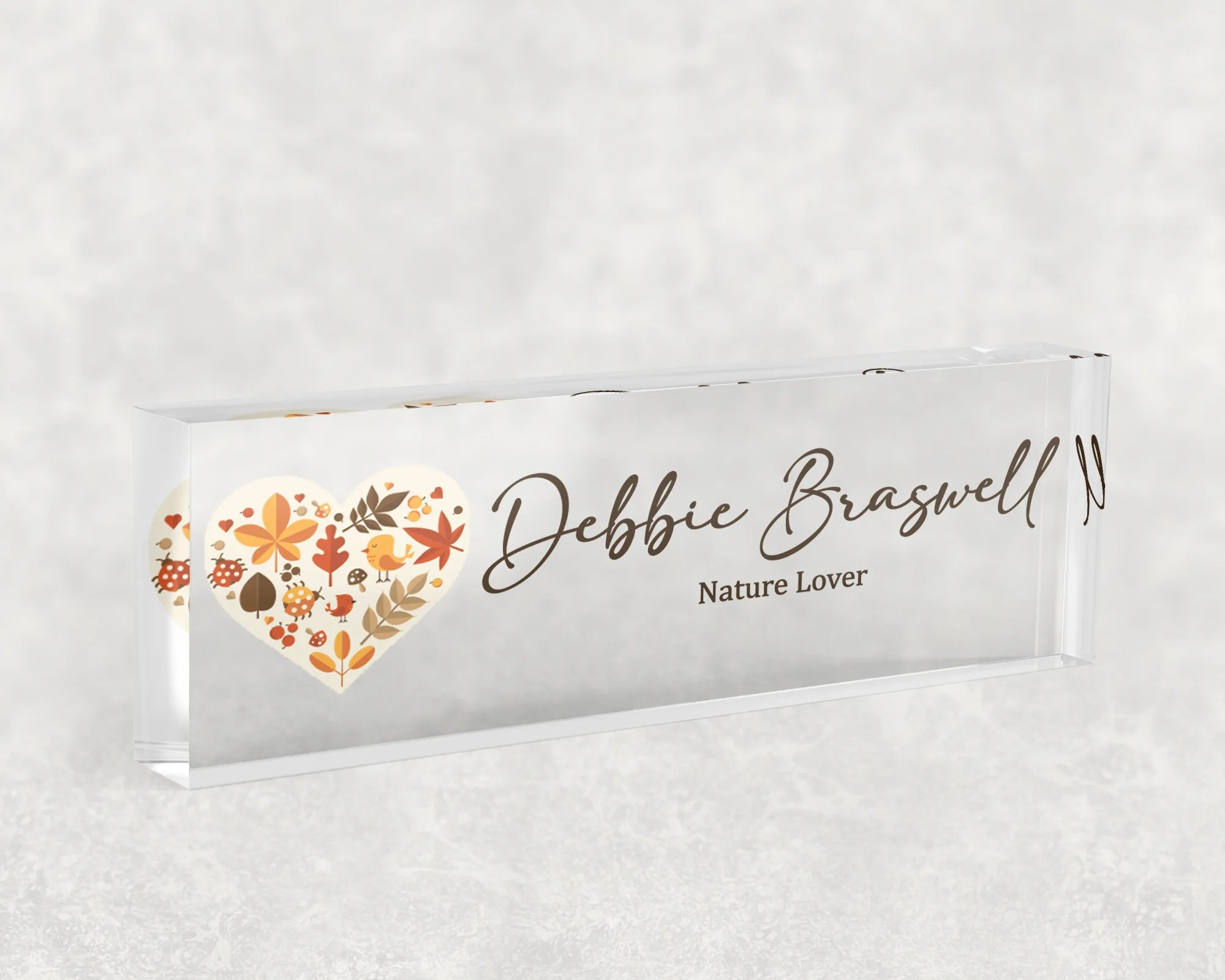 Studio view of a clear acrylic desk name plate with an autumn leaf heart design
